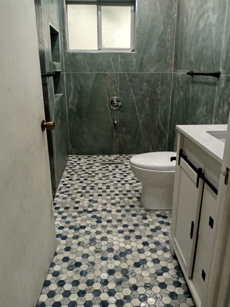Modern green slate large-format tile walls with blue-and-white hexagon mosaic flooring.