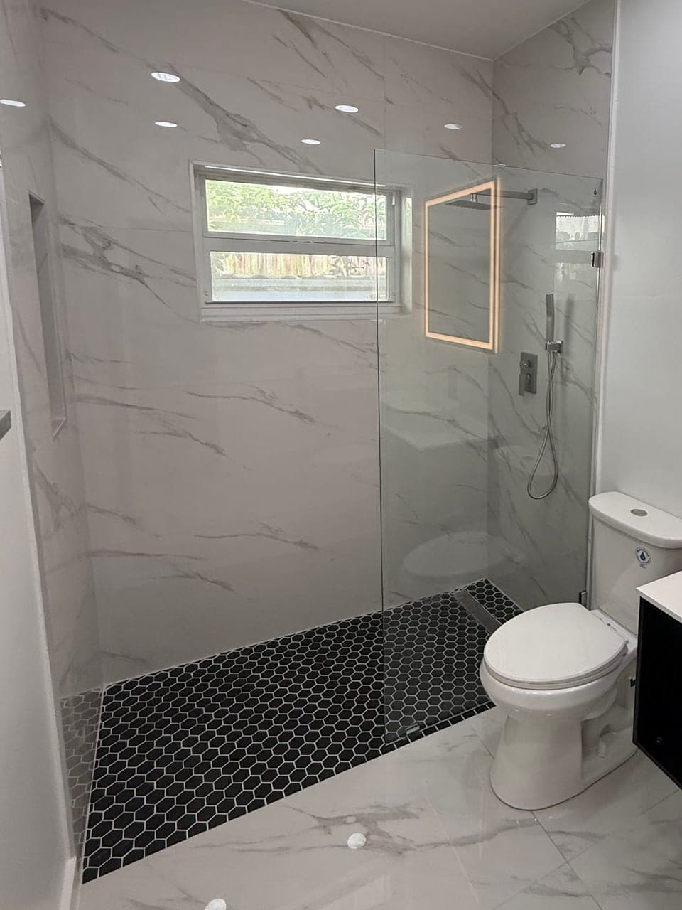 Curbless walk-in shower with black hex mosaic floor and frameless glass after a tub to shower conversion in Glenvar Heights