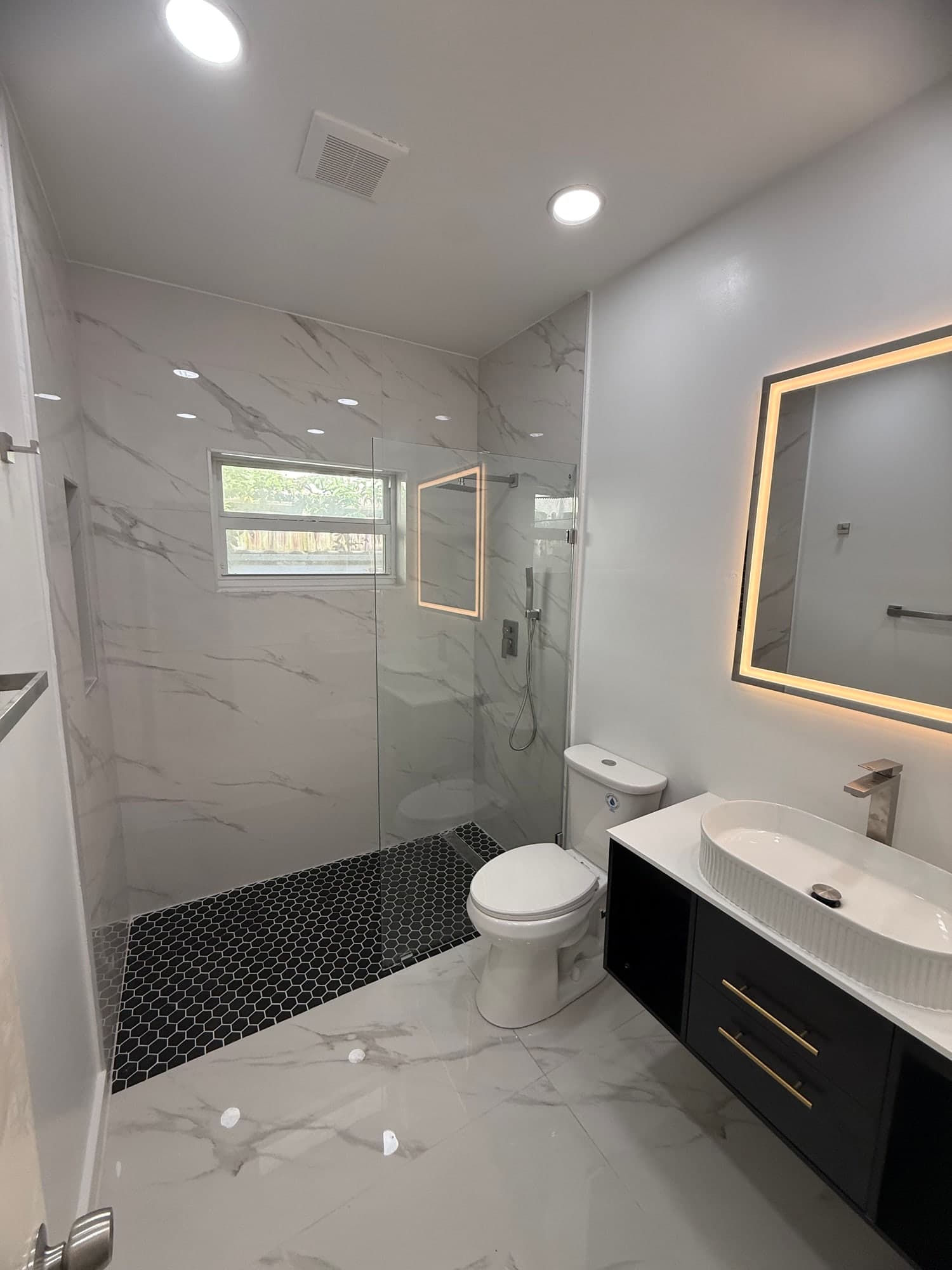 Curbless walk-in shower with a linear drain and porcelain tile after a tub to shower conversion in Glenvar Heights, Miami-Dade