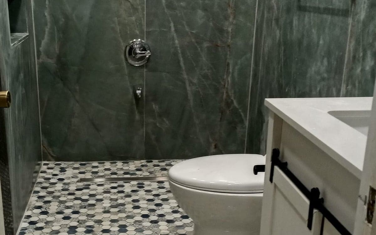 Walk-in shower with green porcelain tile and a new patterned hex mosaic floor through the bathroom in The Crossings, Miami-Dade
