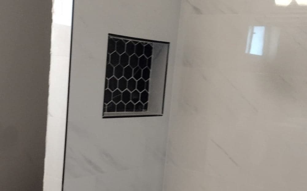 Tiled walk-in shower with white porcelain walls and a black hex mosaic floor built in a tub footprint in The Hammocks, Miami-Dade