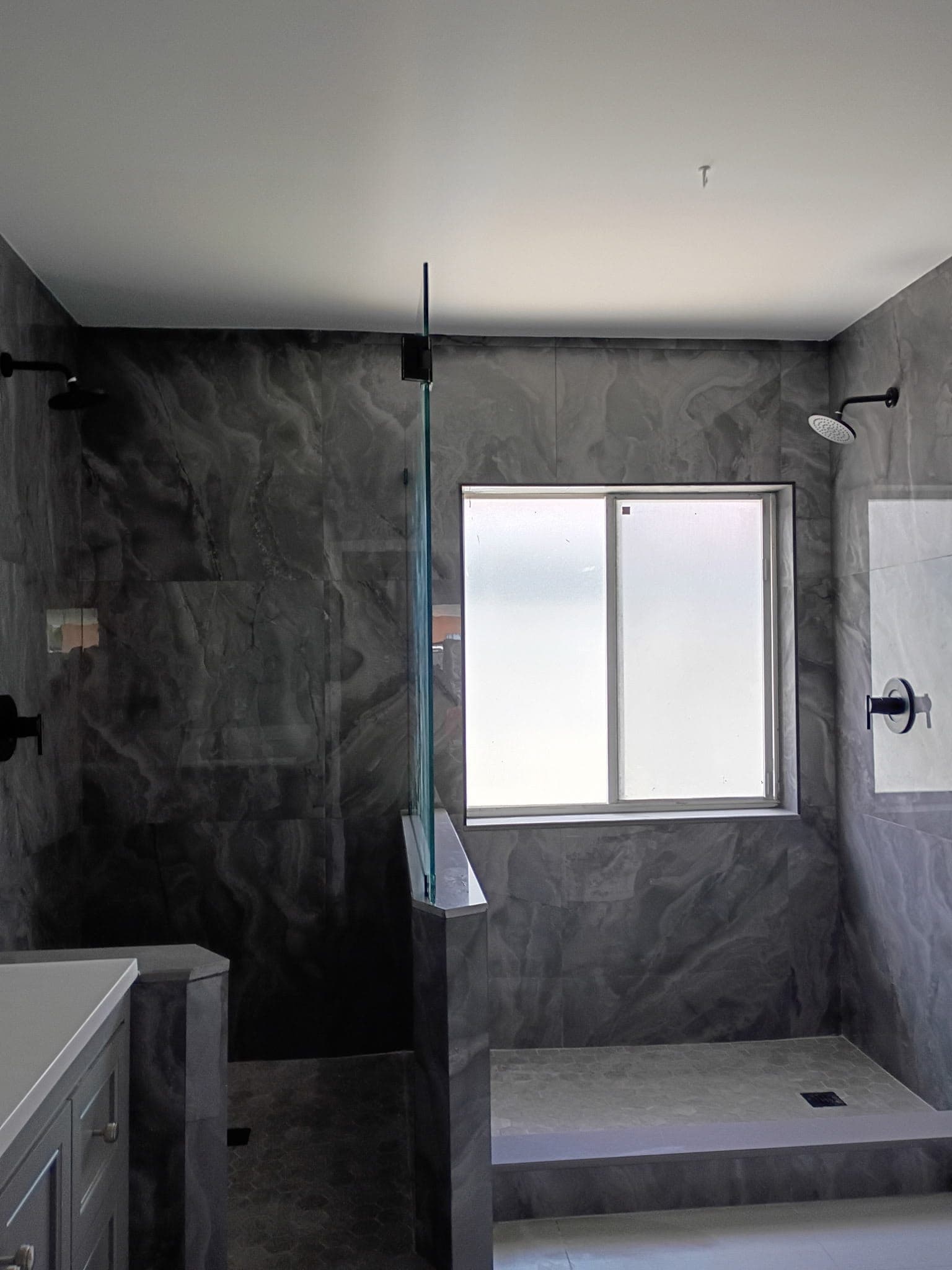 Full bathroom remodel in Pinecrest with green marble look porcelain, a penny tile accent column and a curbless shower with a linear drain