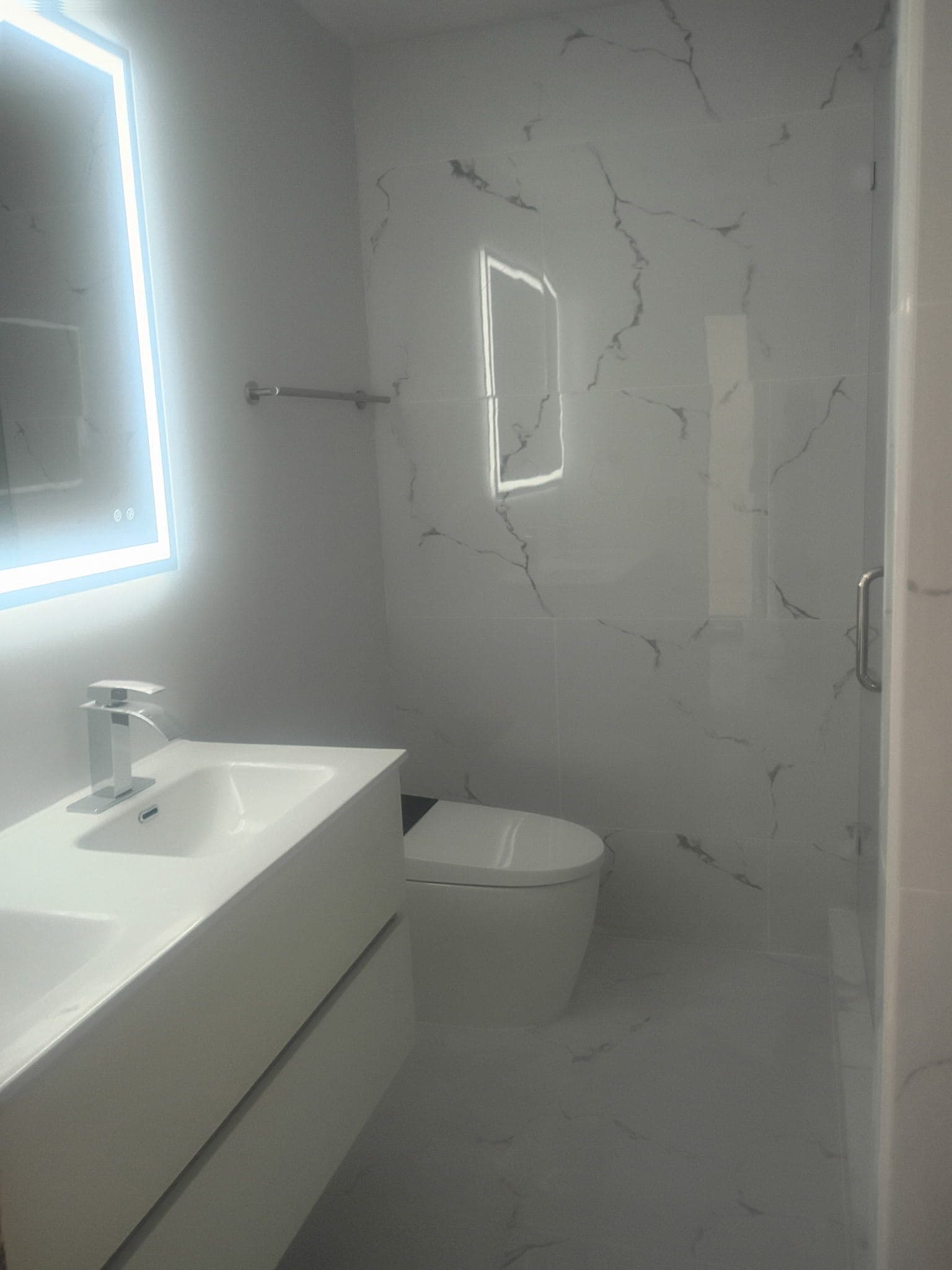 Master bathroom remodel in South Miami with a floating vanity, wall hung toilet and white marble look porcelain