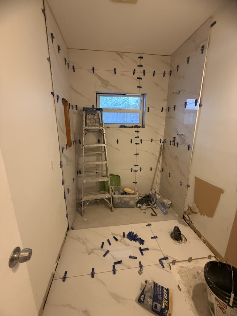 Wall and floor tile installation in progress in a converted shower